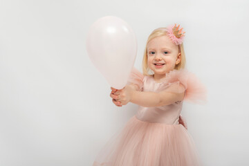 Obraz na płótnie Canvas Little girl in delicate dress with chiffon skirt. Child smiles and holds pink balloon Isolated on white background
