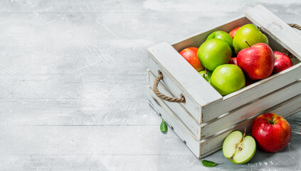 Juicy fresh green and red apples in a wooden box.