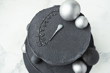 Anniversary black bunk cake with chocolate velvet coating isolated on white background. Birthday cake decorated with silver chocolate spheres and speedometer silhouette indicating age of 30 years