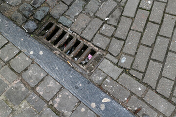 Cobbled street with cigarette butts and drain - Brussels - Belgium