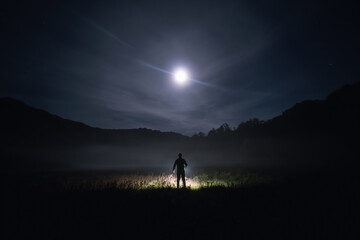 Silhouette of person standing in the dark field with light. Horror halloween concept. strange man....