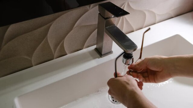 close up of a person washing the eyes glasses underflow water in the white sink with soap. Glasses care concept, hygiene for eyes