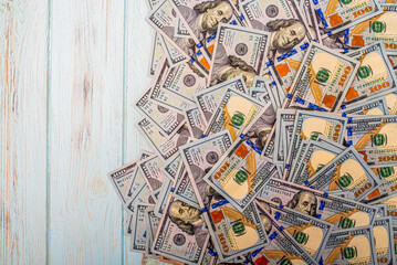 One hundred dollar bills on a blue background. American currency on a wooden background.