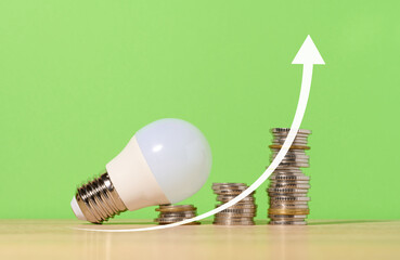 A stack of coins and a glass lamp on a green background, up arrow. The concept of the growth of new...