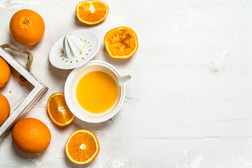 Fresh oranges in tray and juicer.