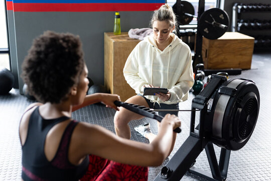 Diverse fit women exercising and using rowing machine at gym