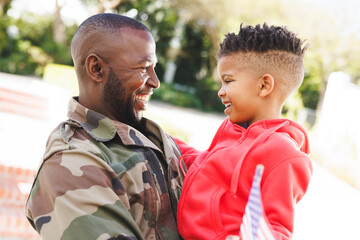 Happy african american father wearing military uniform and his son embracing