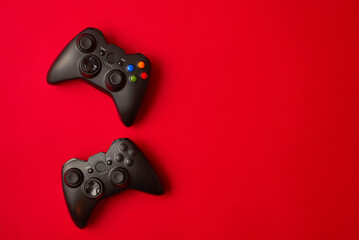 Black video game controller, joystick for game console isolated on red background. Gamer control device close-up © stenkovlad