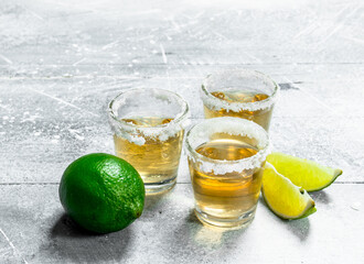 Tequila in a shot glass with lime slices.