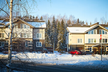 Modern village house in winter day and trees near it in snow in sunny day