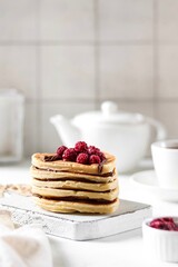 Heart-shaped pancakes lie on top of each other, with chocolate and raspberries on top. Breakfast for Valentine's Day.
