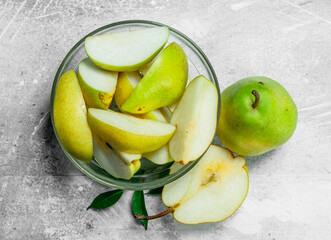 Pieces of fresh pears in bowl with leaves.