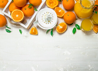 Fresh oranges in tray and juicer.