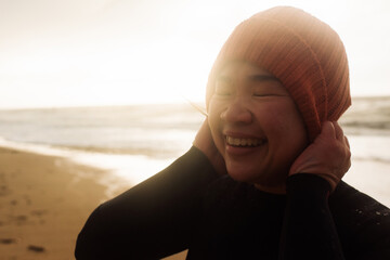 beautiful Asian woman holding her hat ready for cold water swimming