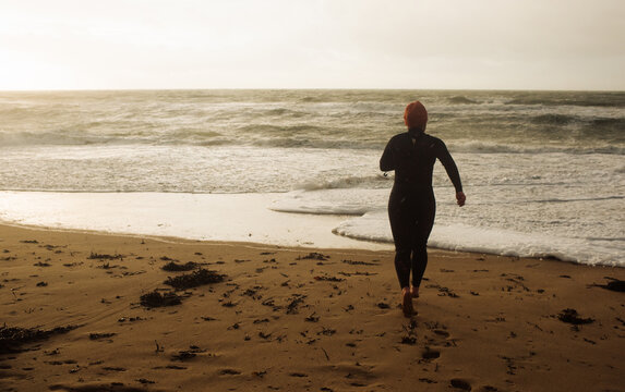 Asian woman running into the cold wild sea to swim