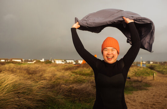 Asian woman holding her coat in the wind running to the sea