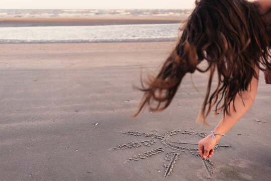 Girl drawing sun on beach