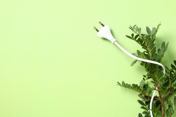 Power plug with plant on green background. Renewable energy, Earth Day or environment protection...