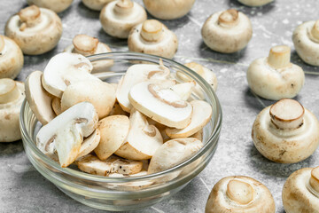 Pieces of fresh mushrooms in the bowl and whole mushrooms.