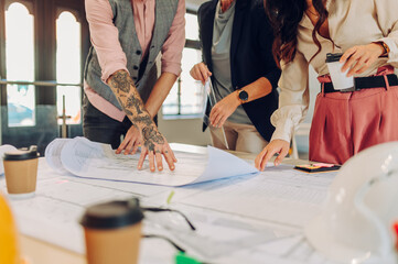Multiracial team of architects having a meeting while using blueprints