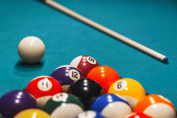 Colorful billiard balls with numbers with cue sticks and rack on blue table