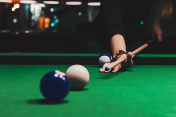 Player holding que and aiming to billiard white ball. White ball on gree poll table.