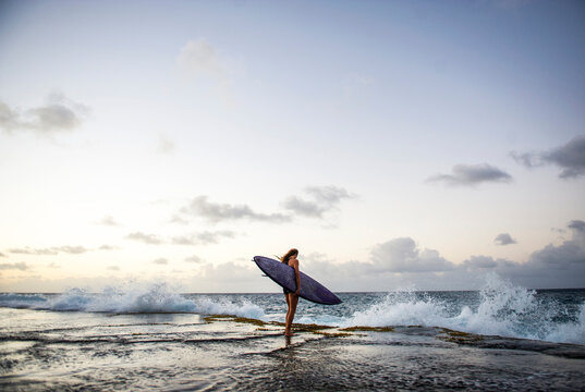 Surfer looking outwards at the waves at sunset