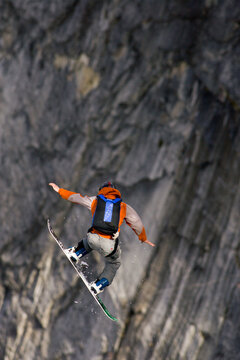 A male snowboard BASE jumper jumps off an 800 foot granite cliff.