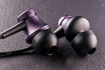 A symbol of the intersection of youth culture, sport and modern technology, as a pair of earbuds sits against a black background, representing the role of music in enhancing performance and style - 561145511