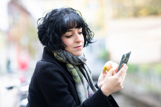 Young Woman With Apple And Smart Phone Outside