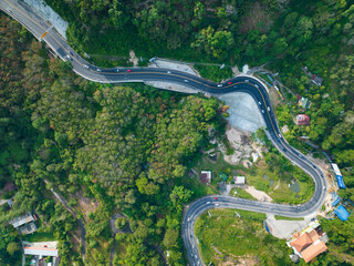 Aerial view top down drone shot above the winding mountain road between the trees rainforest,Phuket Thailand,in summer season weather, Car driving through the curve road