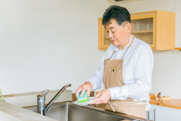 お皿洗い・食器洗いをするアジア人の高齢者男性（疲労）
