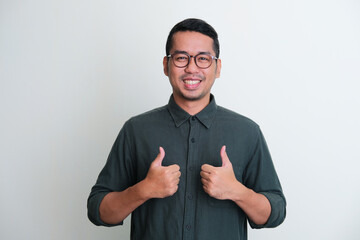 Adult Asian man smiling at the camera and give two thumbs up