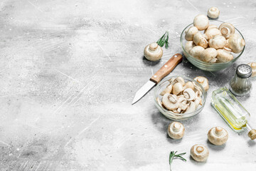 Fototapeta na wymiar Sliced mushrooms in bowl with oil, pepper and knife.
