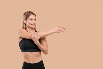 Athletic woman stretching on beige background, space for text