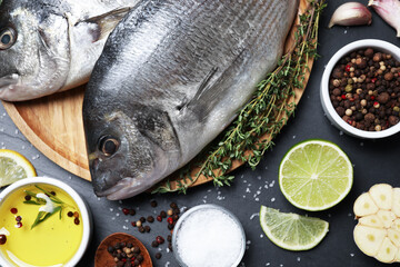 Flat lay composition with fresh raw dorado fish and ingredients on black table