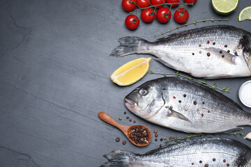 Flat lay composition with fresh raw dorado fish and ingredients on black table, space for text
