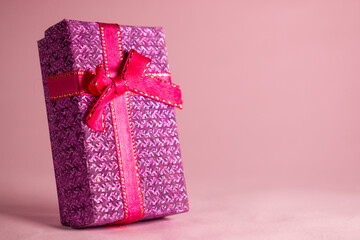 Pink gift box with bow on pink background 