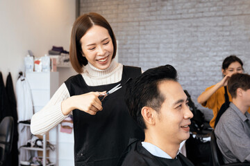 Asian female hairdresser making haircut for two male customer with male hairstyle in qualified...