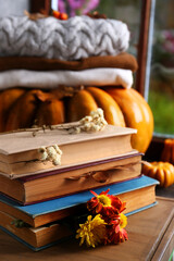 Stack of books with autumn leaves and flowers as bookmarks on wooden table