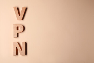 Acronym VPN made of wooden letters on beige background, flat lay. Space for text