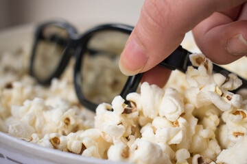 Close up of hand taking 3d glasses from a popcorn pot 