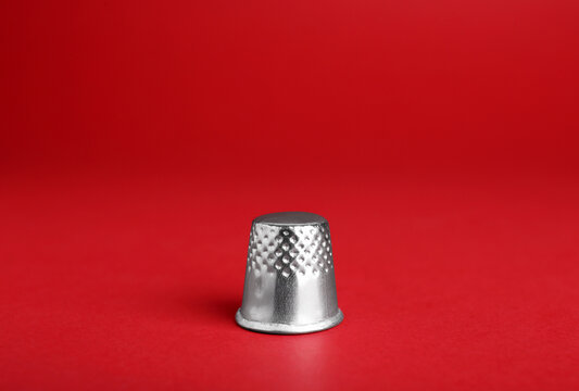 Silver thimble on red background. Sewing accessory