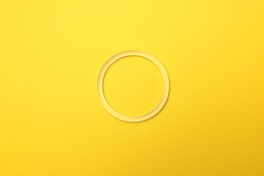 Diaphragm vaginal contraceptive ring on light yellow background, top view