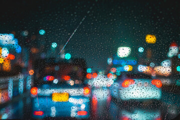 Raindrops on car windshield during night driving on a rainy evening traffic jam