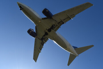 Fototapeta na wymiar Vista inferior del fuselaje de un avión comercial volando a baja altura 