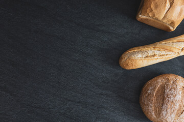 Two breads and one french baguette on a black background.