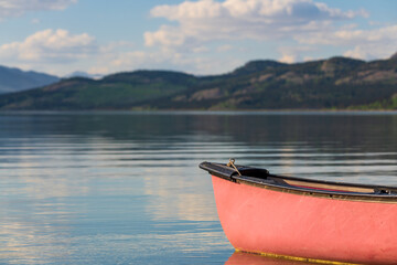 Summertime views in northern Canada with calm lake and mountain views. Red canoe in focus view. 