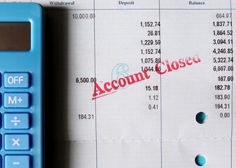 Blue calculator and pen on bank pass book with stamp ACCOUNT CLOSED, concept of bank account was...