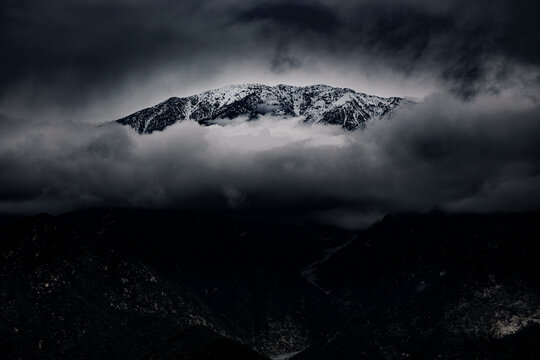 Glendora Ridge of Los Angeles on an overcast cloudy day with a mountain peak with snow. Freezing temperatures  with a cloud beneath the mountains